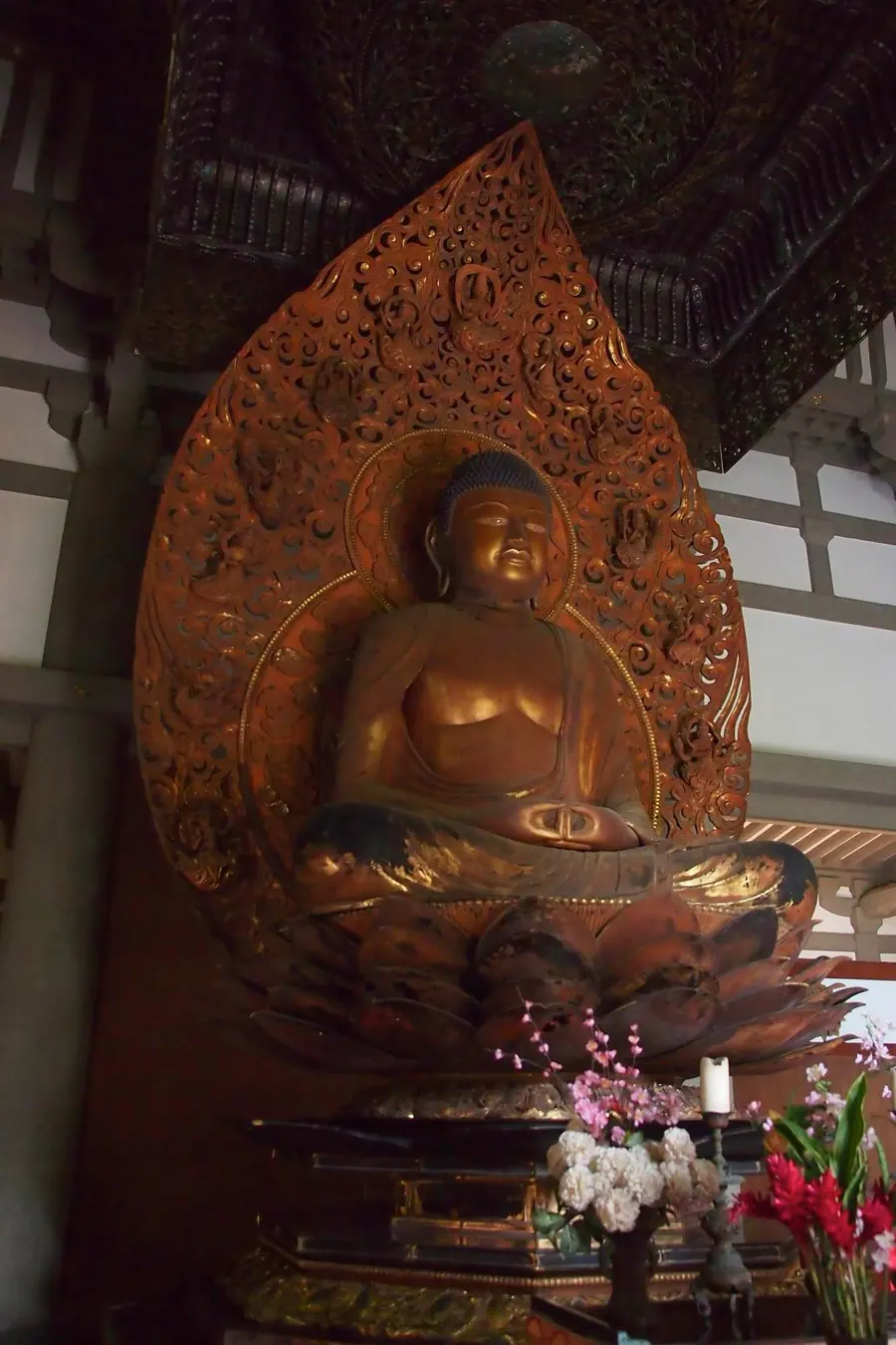 Gilded seated Buddha in a temple hall, hands in meditation posture.