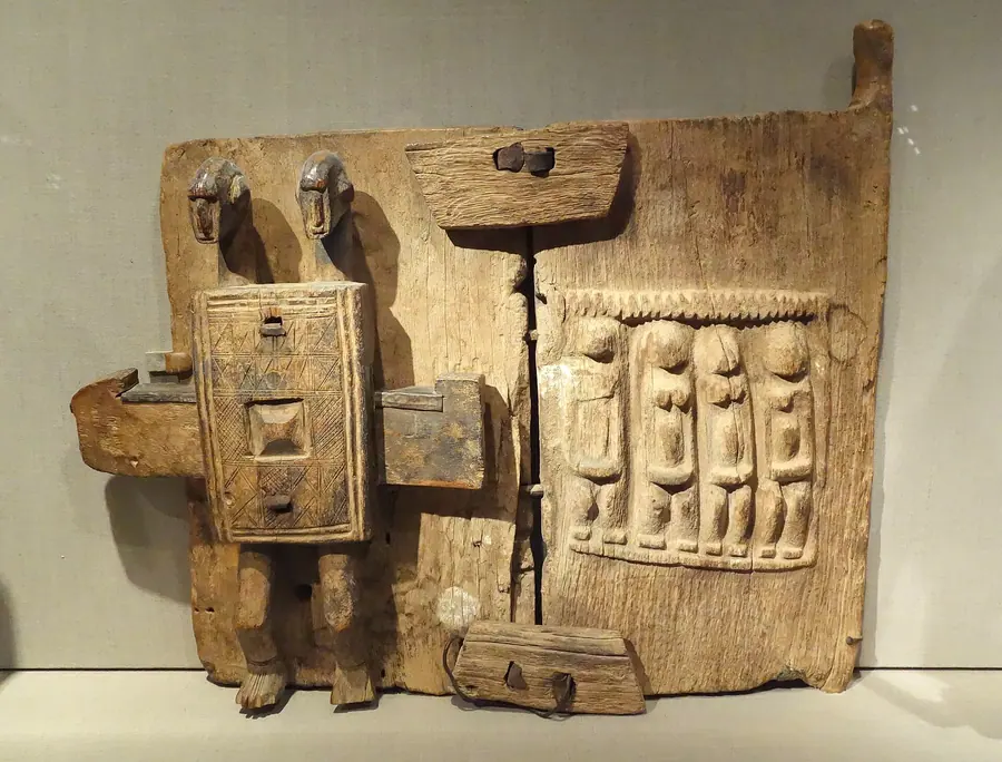 Carved wooden door panel covered in rows of small standing figures.
