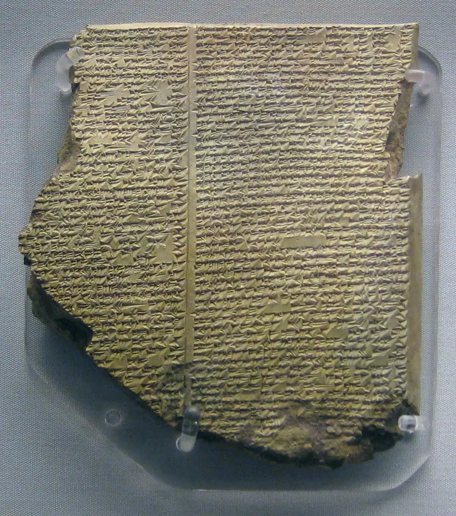Broken clay tablet covered in dense cuneiform, the surface chipped along its upper edge.