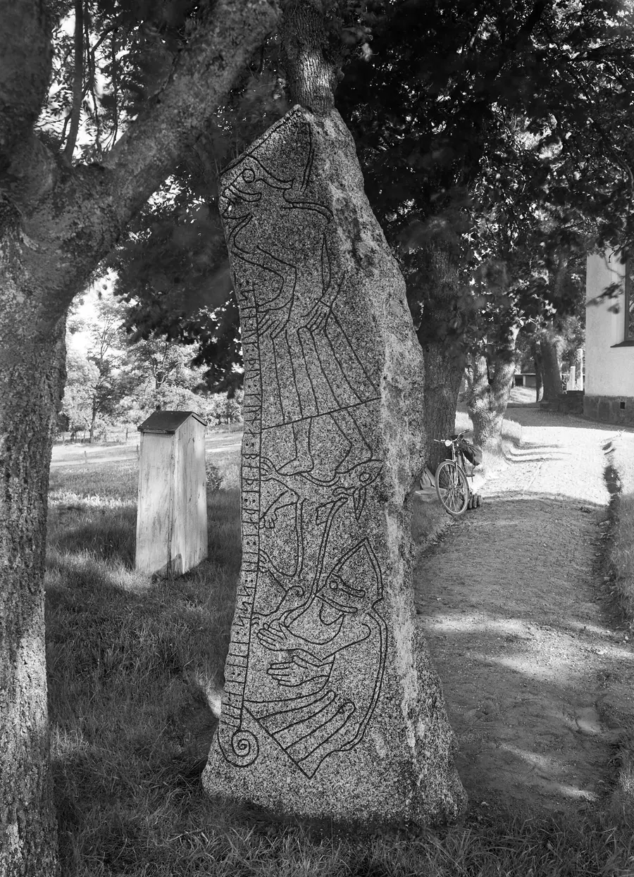 Swedish runestone with a figure and a beast at its base.