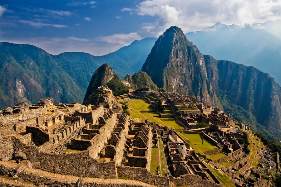 Stone Inca settlement on a high ridge between steep green peaks.
